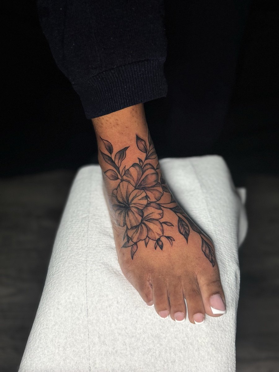 Red and black floral tattoo across the top of a foot.