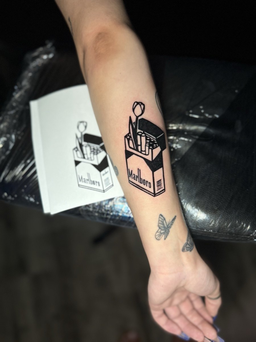Small black and grey bottle illustration tattoo near the wrist.