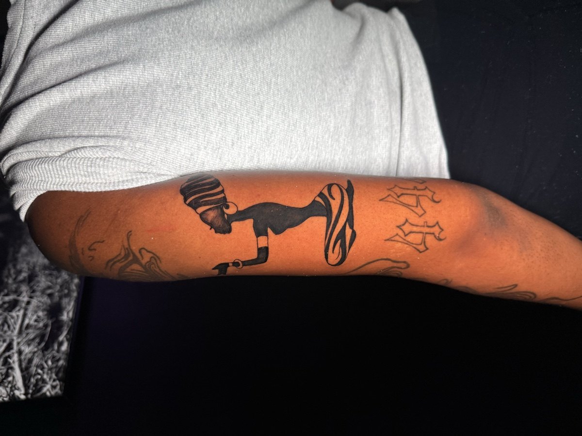 Black and grey animal silhouette scene tattoo wrapping a forearm.