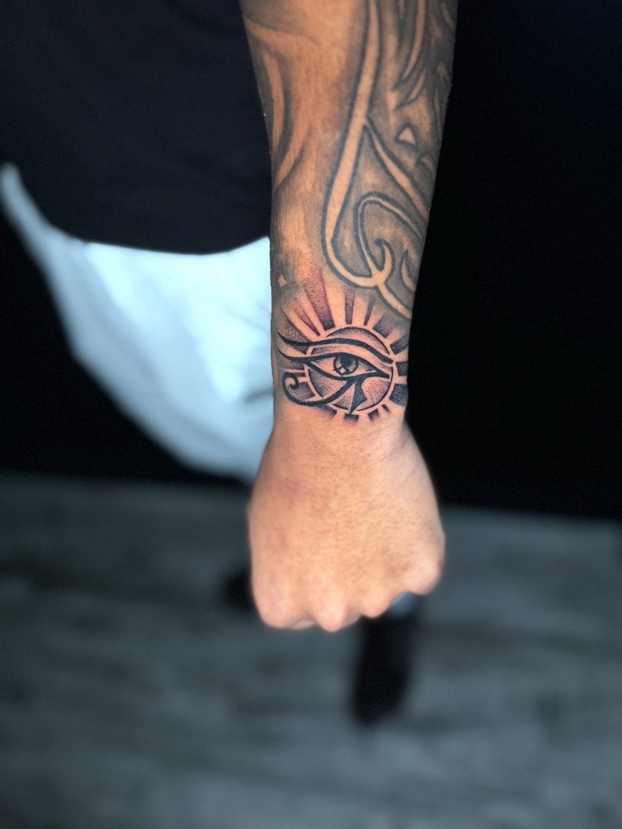Ornamental blackwork cuff tattoo extending along a forearm.